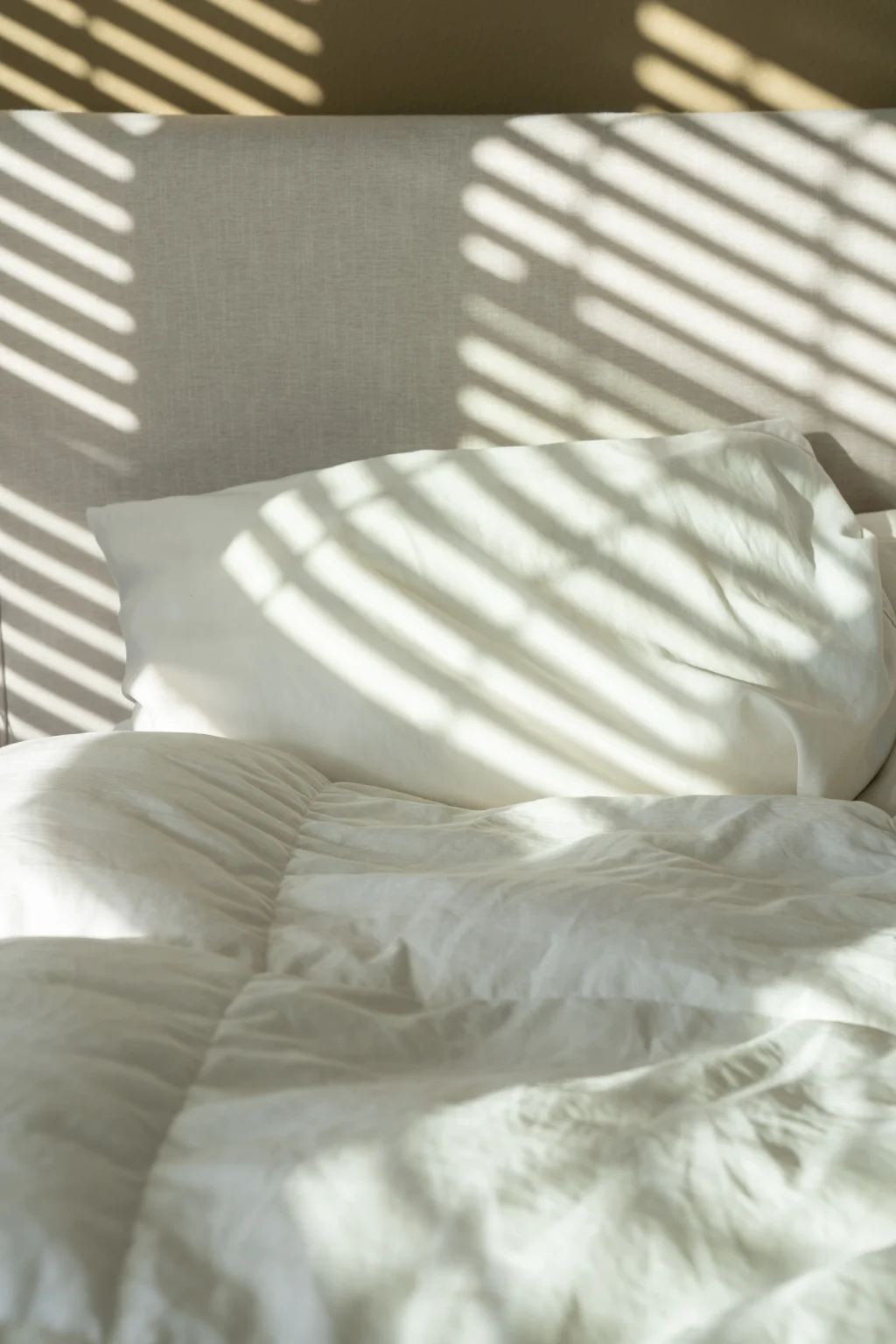 Wit beddengoed met strepen zonlicht erover