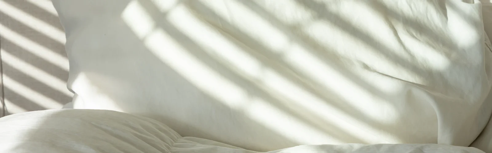 Wit beddengoed met strepen zonlicht erover