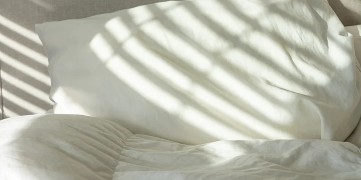 Wit beddengoed met strepen zonlicht erover