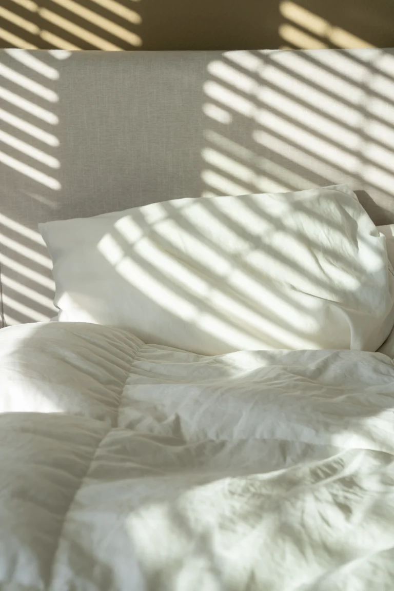 Wit beddengoed met strepen zonlicht erover