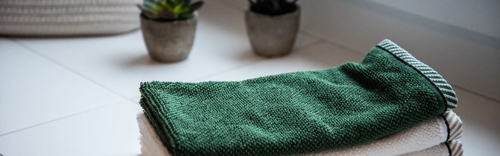 Een stapel opgevouwen handdoeken naast een plant