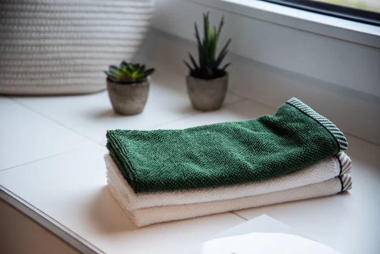Een stapel opgevouwen handdoeken naast een plant