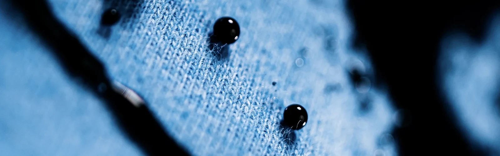 Waterdruppels op een blauwe stof van dichtbij