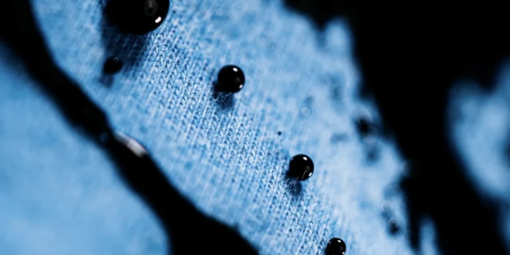 Waterdruppels op een blauwe stof van dichtbij