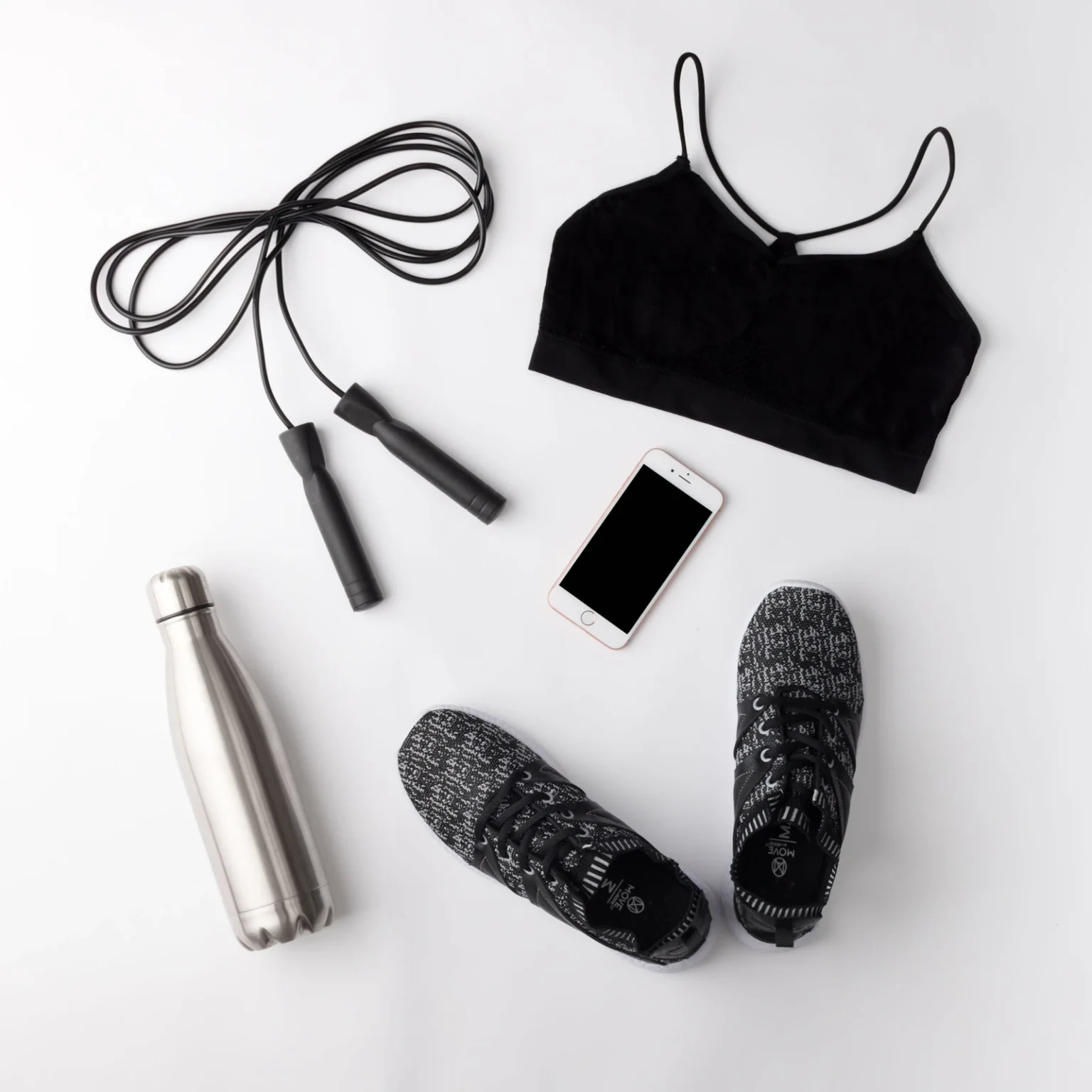 Sportkleding, schoenen en een bidon naast elkaar