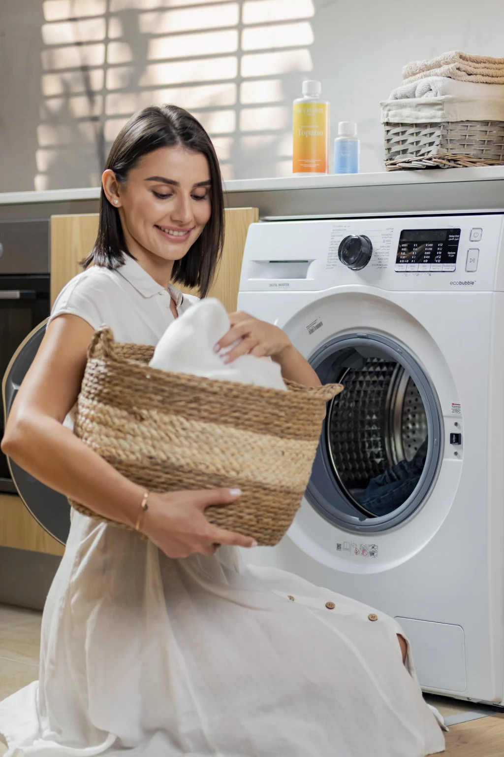 Iemand tilt een wasmand naast een wasmachine