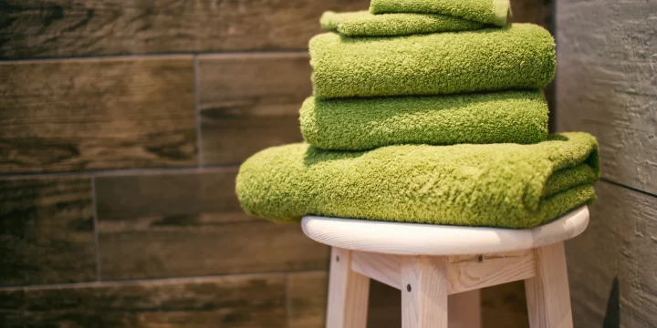 Opgevouwen groene handdoeken op een houten kruk