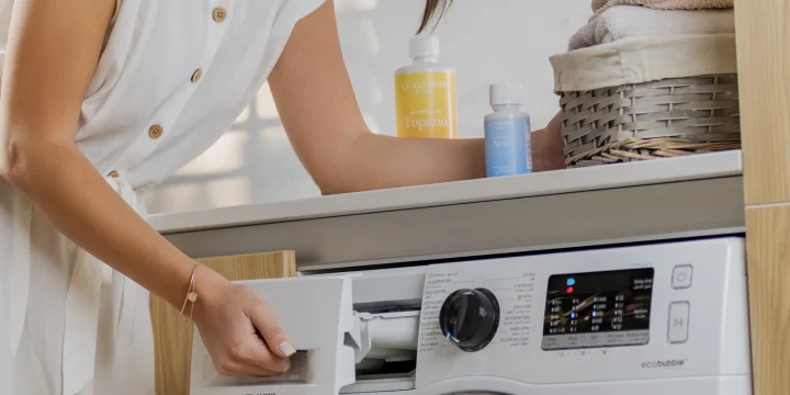 Iemand vult de lade van een wasmachine met vooropening