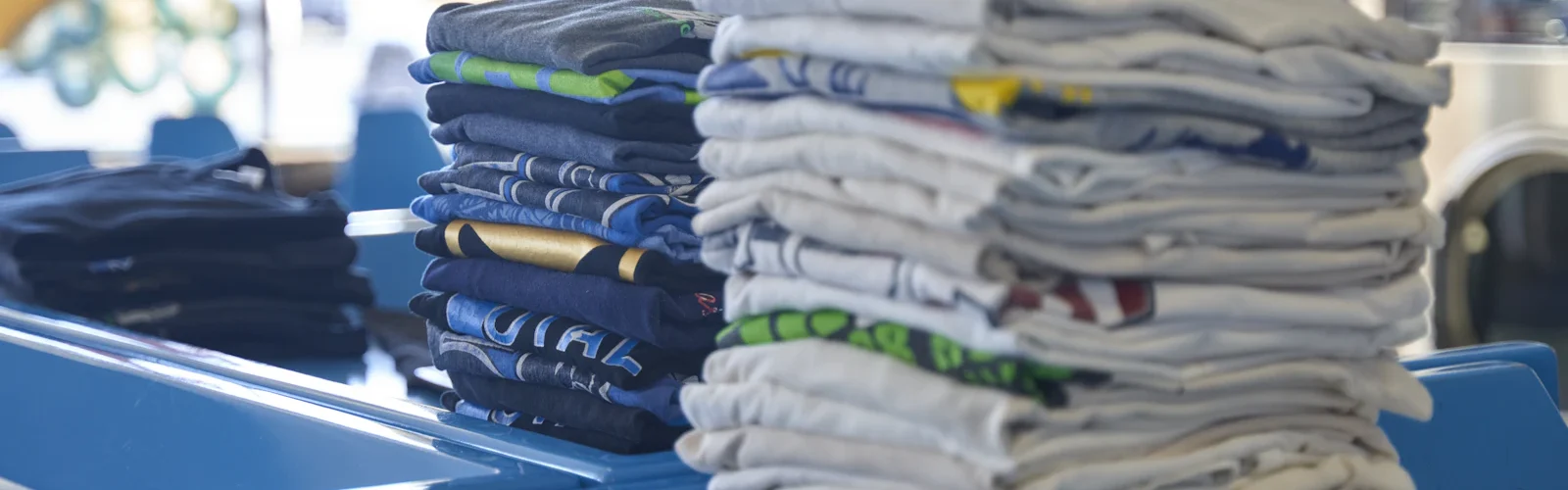 Een stapel gevouwen kleding op een tafel in een wasserette