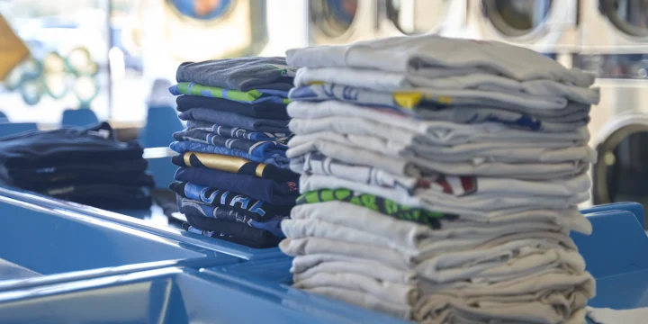 Een stapel gevouwen kleding op een tafel in een wasserette