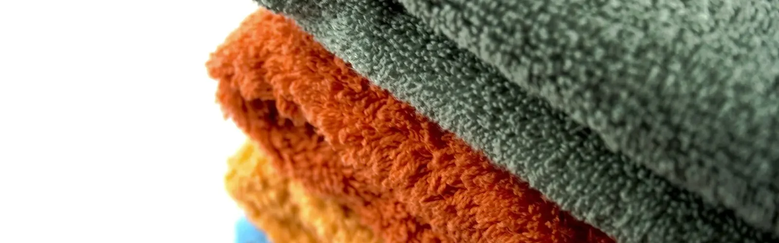 Vier opgevouwen handdoeken in verschillende kleuren op elkaar