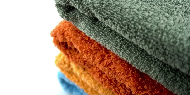 Vier opgevouwen handdoeken in verschillende kleuren op elkaar