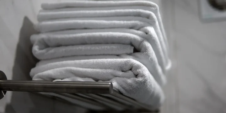 Een stapel opgevouwen witte handdoeken op een handdoekrek
